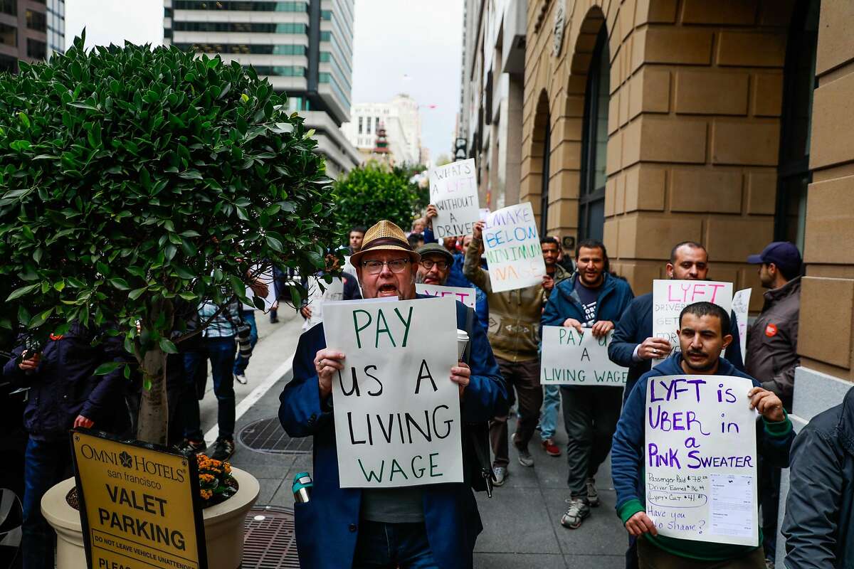Lyft driver Tom Hoffman (center) and others cheer at the start of a protest against Lyft's paycuts as well as the company going public on Friday in San Francisco , California, on Monday, March 25, 2019. Drivers argue that their share has been cut significantly and that they are the backbone of the company.