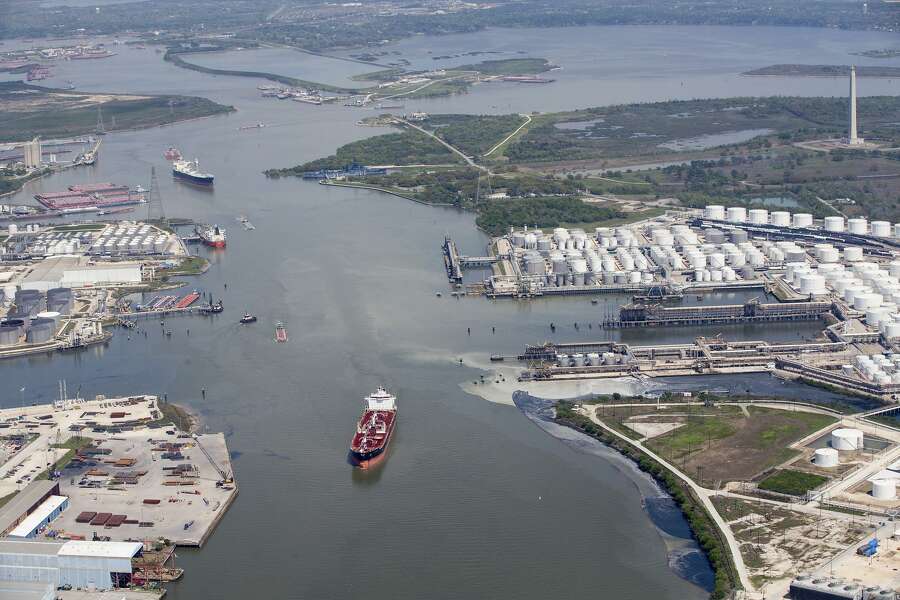 In a Wednesday, March 20, 2019 photo, maritime traffic moves through the Houston Ship Chanel past the site of now-extinguished petrochemical tank fire at Intercontinental Terminals Company in Deer Park, Texas. Air quality and water pollution from the fire's runoff, seen on the right, into the ship channel are some of the concerns in the aftermath of the blaze. (Brett Coomer/Houston Chronicle via AP)