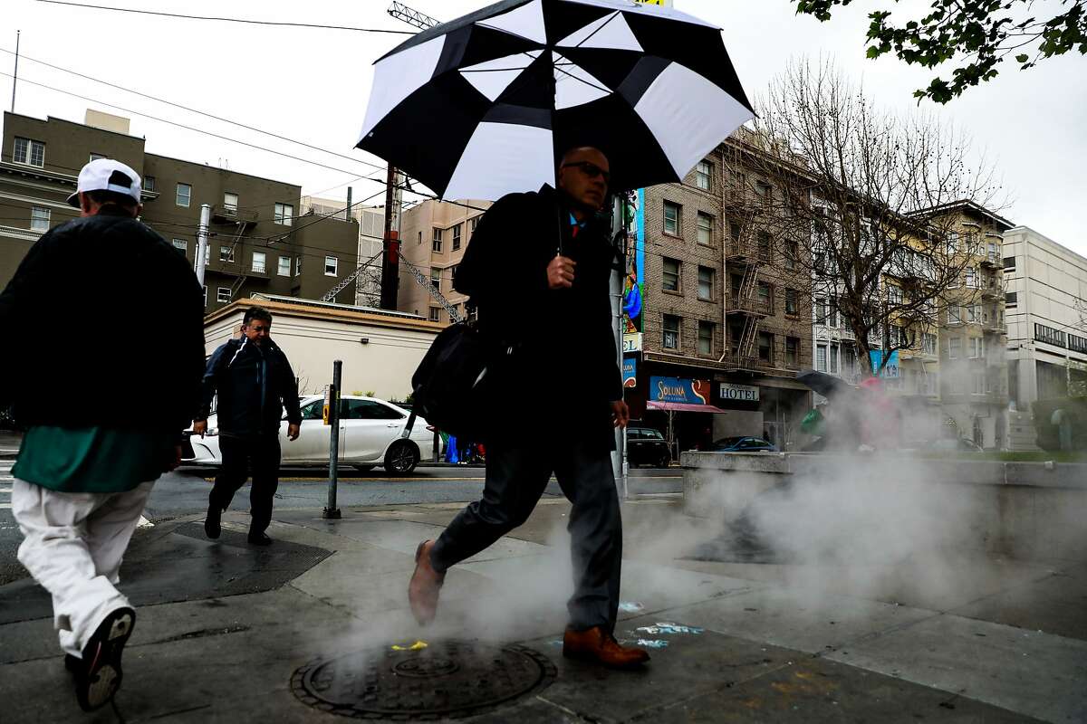People walk on Larkin and McAllister Streets in the rain in San Francisco , California, on Monday, March 25, 2019.