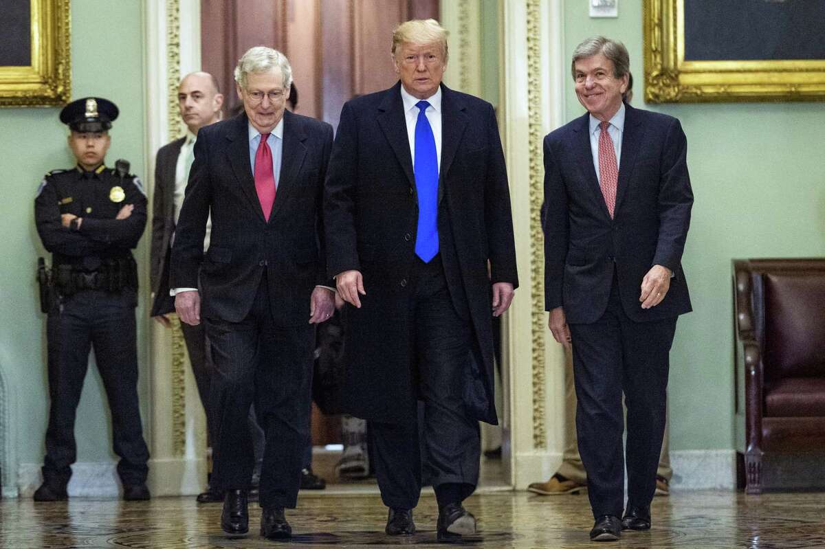 President Donald Trump is flanked by Senate Majority Leader Mitch McConnell (R-Ky.), left, and Sen. Roy Blunt (R-Mo.) as he arrives for a luncheon with Senate Republicans at the Capitol on Tuesday, March 26, 2019.