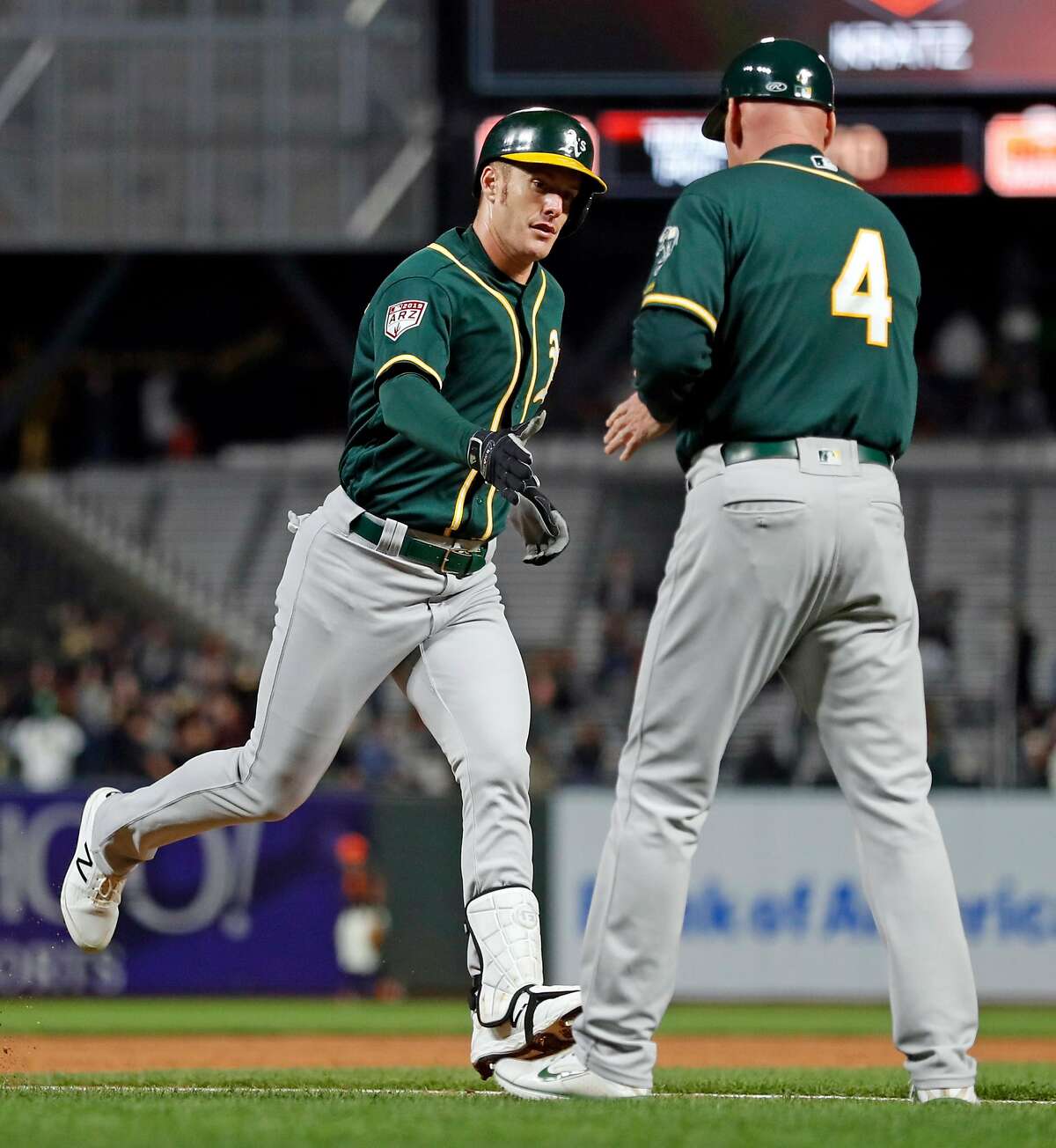 Oakland Athletics' Mark Canha is greeted by Matt Williams as Canha rounds third base after hitting 2-run home run in 4th inning against San Francisco Giants' Jeff Samardzija in Bay Bridge Series game at Oracle Park in San Francisco, Calif., on Tuesday, March 26, 2019.
