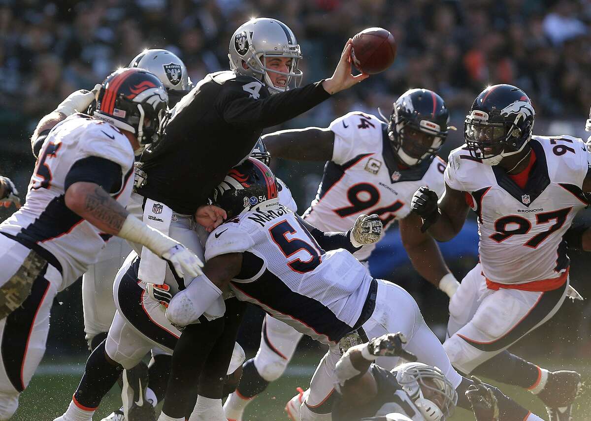 Oakland Raiders quarterback Derek Carr (4) gets rid of the ball as he is pressured by Denver Broncos linebacker Brandon Marshall (54) during the third quarter of an NFL football game in Oakland, Calif., Sunday, Nov. 9, 2014. Carr threw the ball to offensive tackle Khalif Barnes, who fumbled; the ball was recovered by Broncos cornerback Chris Harris. (AP Photo/Marcio Jose Sanchez)