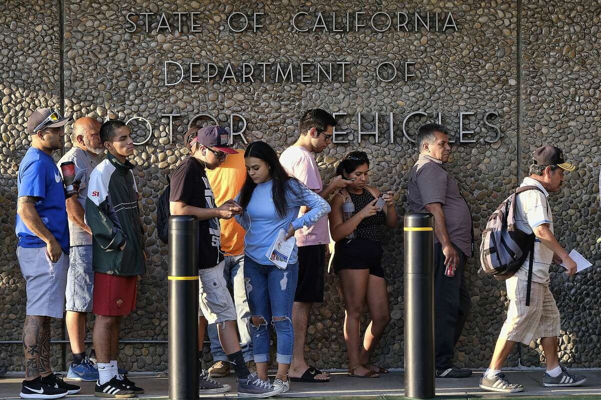 FILE - In this Aug. 7, 2018, file photo, people line up at the California Department of Motor Vehicles prior to opening in the Van Nuys section of Los Angeles. An audit issued by California Department of Finance and released on Wednesday, March 27, 2019, say the DMV didn't properly prepare for customers seeking to get new federally approved drivers' licenses, leading to hours-long wait times. (AP Photo/Richard Vogel, File)