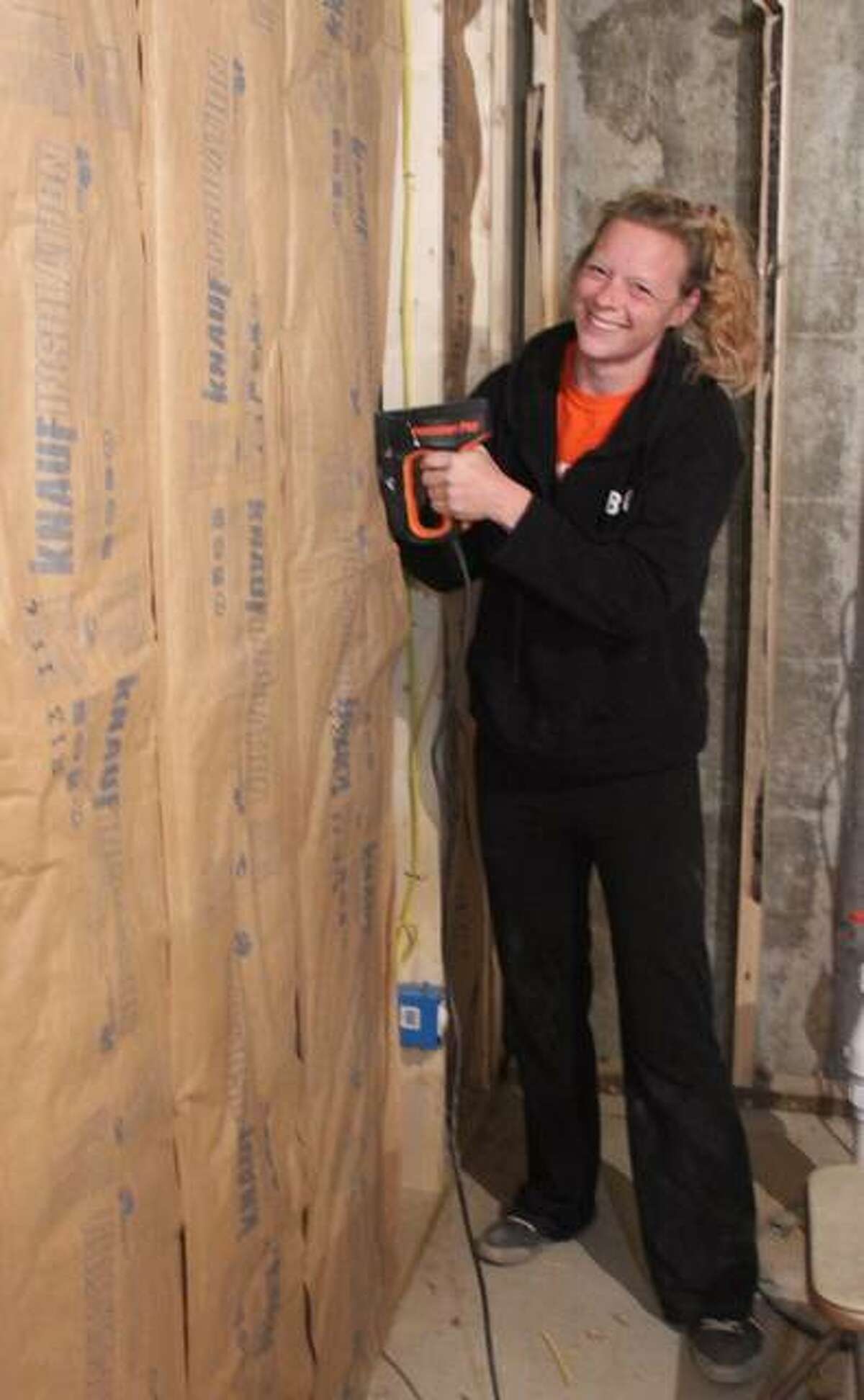 Laura Flamuth, the future recipient of the house, helps finish insulating the walls.