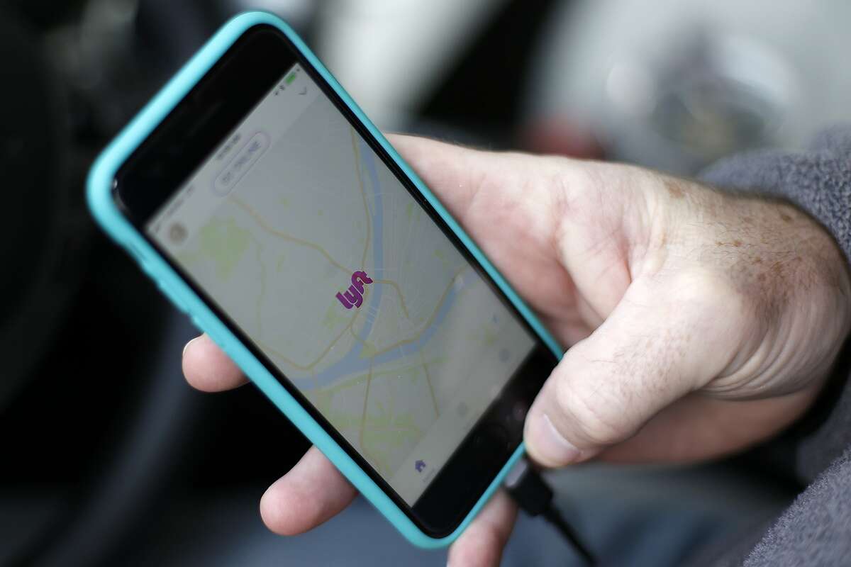 FILE- In this Jan. 31, 2018, file photo, a Lyft driver opens the Lyft app on his phone while waiting for a fare in Pittsburgh. Lyft set the price for its stock at $72 per share late Thursday, March 28, 2019, setting the stage for the ride-hailing pioneer's hotly anticipated stock market debut. (AP Photo/Gene J. Puskar, File)