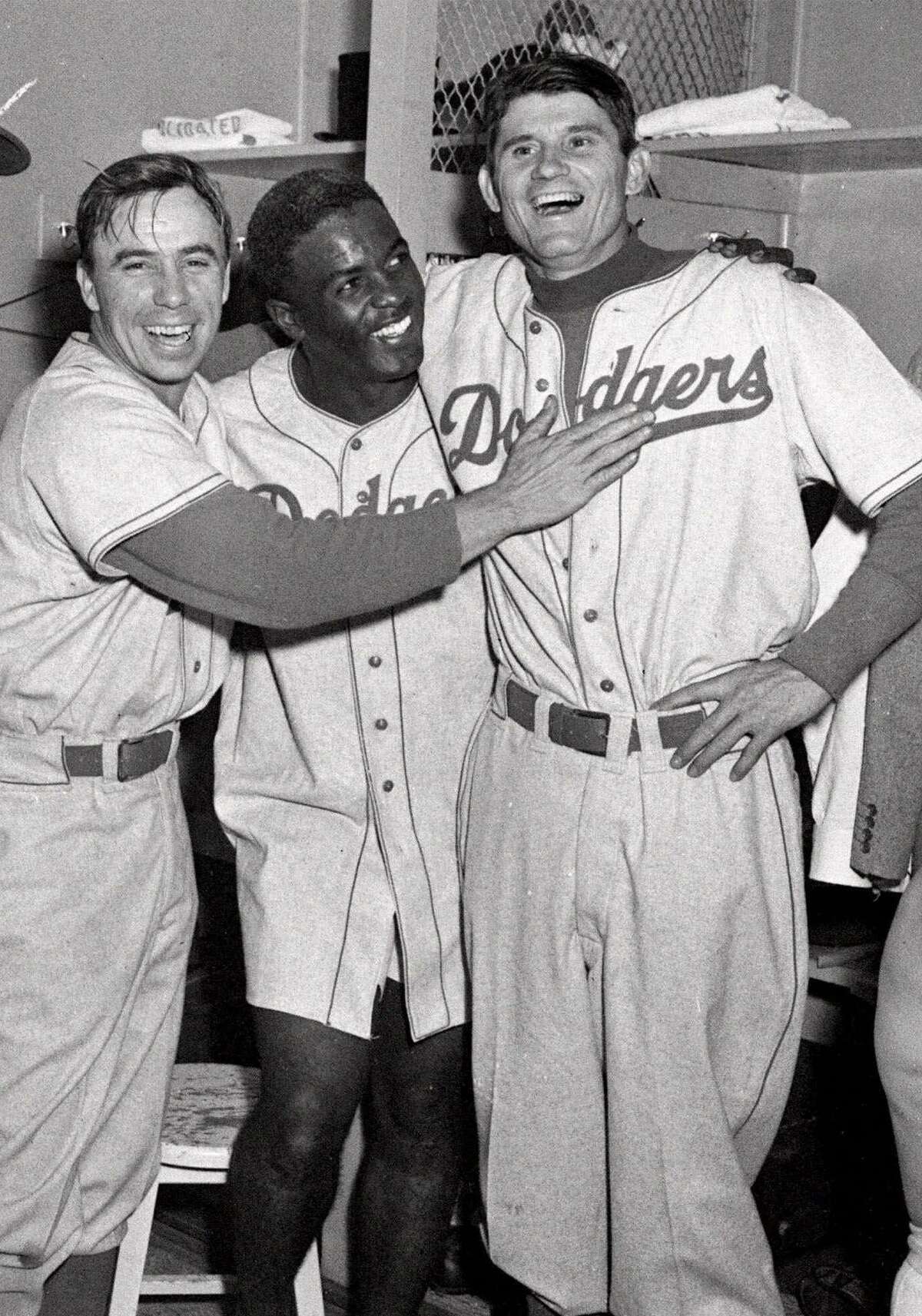 Brooklyn Dodgers from left, Pee Wee Reese, Jackie Robinson, and Preacher Roe are a happy trio in the clubhouse after the Dodgers beat the Yankees 5-3 in the third game of the World Series at Yankee Stadium in New York City, in this Oct. 3, 1952 file photo.