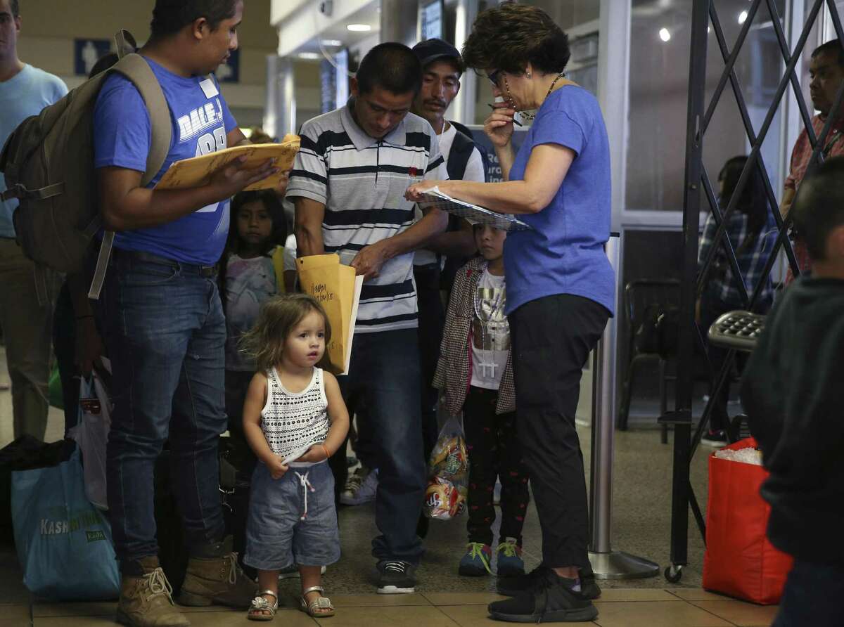 Two-year-old Juliet Giron, waits as her father, Brian Giron, 24, is helped by Interfaith Welcome Coalition volunteer Carolina Barrera at the Greyhound Bus station in San Antonio, Thursday, July 26, 2018. The Honduran family was released earlier today in McAllen. They were kept together during their ICE detention.