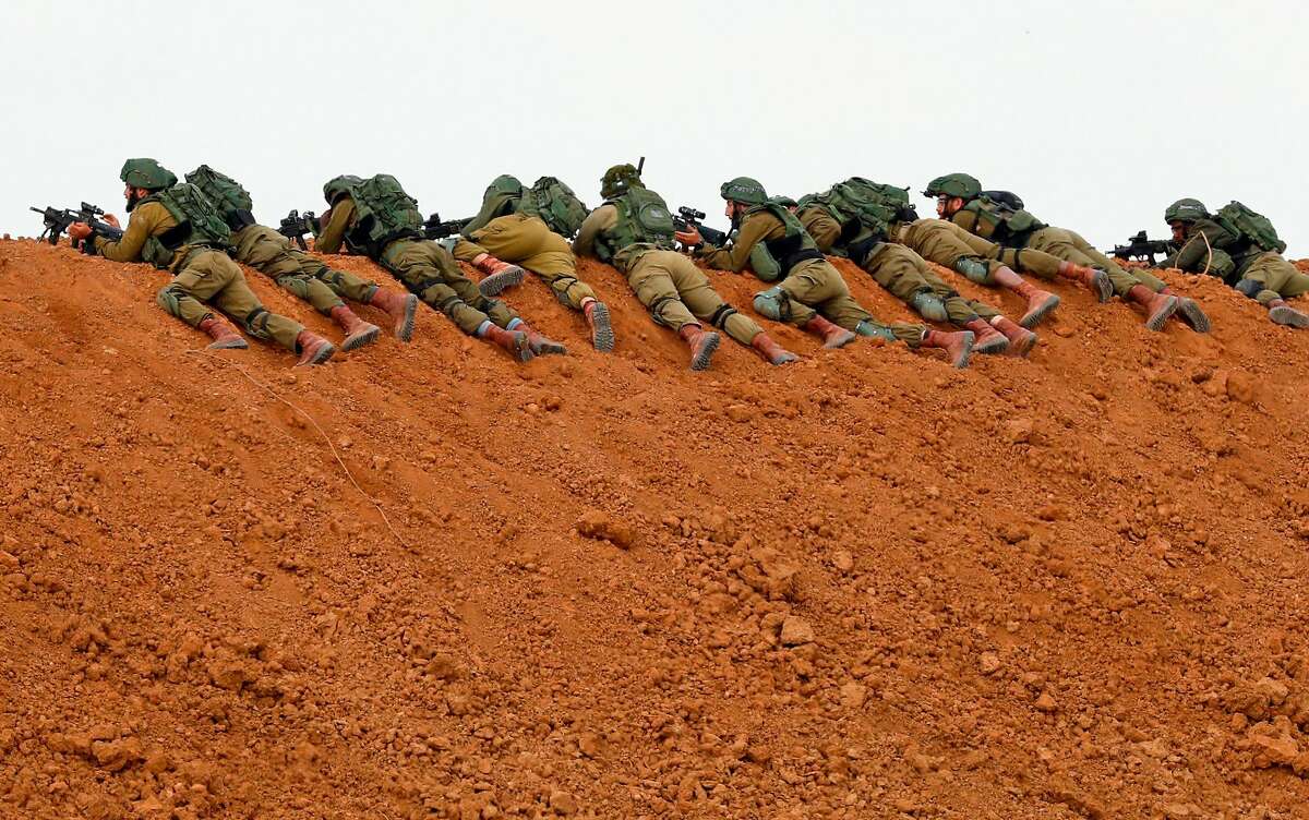 (FILES) In this file photo taken on March 30, 2018 Israeli soldiers keep position as they lie prone over an earth barrier along the border with the Gaza Strip in the southern Israeli kibbutz of Nahal Oz as Palestinians demonstrate on the other side commemorating Land Day. - A year after the start of protests, labelled the Great March of Return, and clashes on the Gaza-Israel border, more than 200 Palestinians have been killed by Israeli fire. More than 8,000 operations for other often serious but not life-threatening conditions -- such as gallstones or hip replacements -- have been postponed in Gaza hospitals according to the WHO. Explosive devices, stones and fireworks have been used against Israeli forces. There has been occasional gunfire, with one soldier killed by a Palestinian sniper. (Photo by Jack GUEZ / AFP)JACK GUEZ/AFP/Getty Images