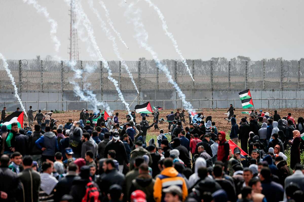 Tear gas canisters fall amongst Palestinian protesters during a demonstration near the border with Israel in Malaka east of Gaza City on March 30, 2019, as Palestinians mark the first anniversary of the "March of Return" border protests. - This marks the first anniversary of the often violent weekly border demonstrations in which around 200 Palestinians and an Israeli soldier have been killed, coming just 10 days before a keenly contested general election in Israel. The border protests peaked in May 2018, when Israeli forces shot dead at least 62 Palestinians in a single day in clashes over the transfer of the US embassy to Israel to the disputed city of Jerusalem. (Photo by MAHMUD HAMS / AFP)MAHMUD HAMS/AFP/Getty Images