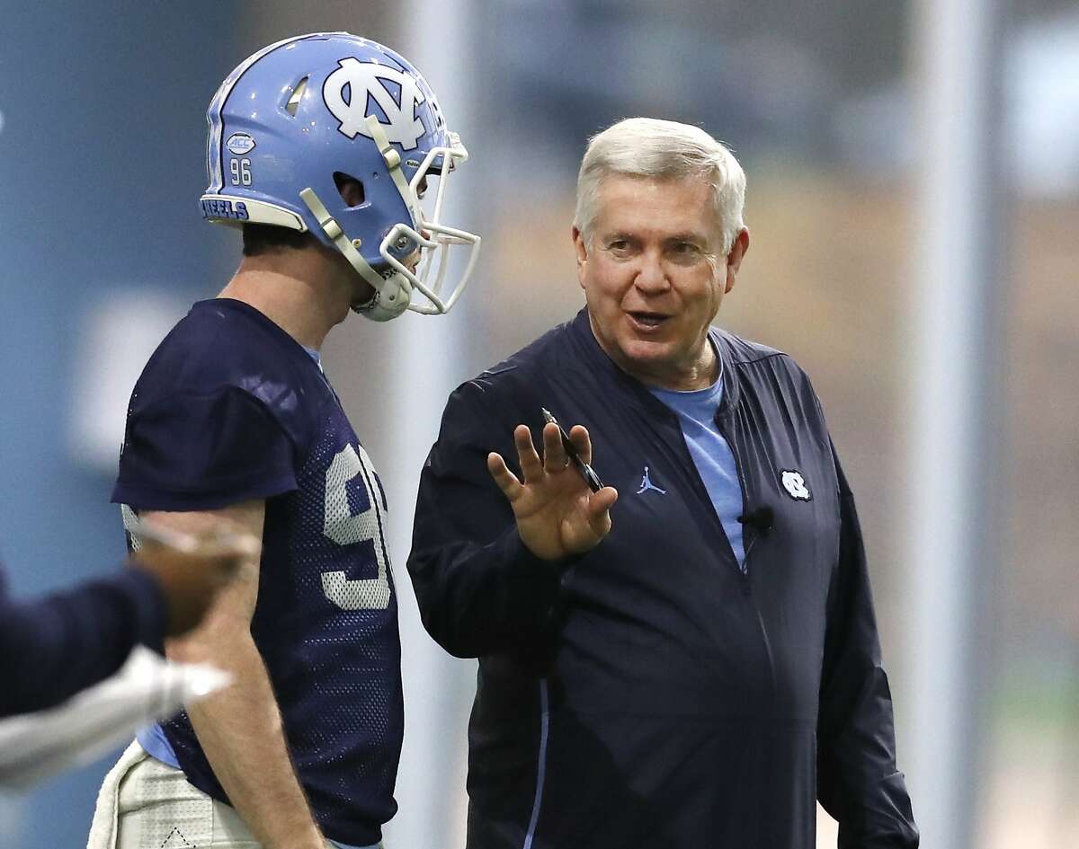 FILE - In this March 3, 2019, file photo, North Carolina head coach Mack Brown talks with Cooper Graham (96) during UNC's first spring football practice, in Chapel Hill, N.C. Brown is back for his second stint as coach of the Tar Heels and is pushing his players for more focus, execution and urgency in spring drills. (Ethan Hyman/The News & Observer via AP, File)/=