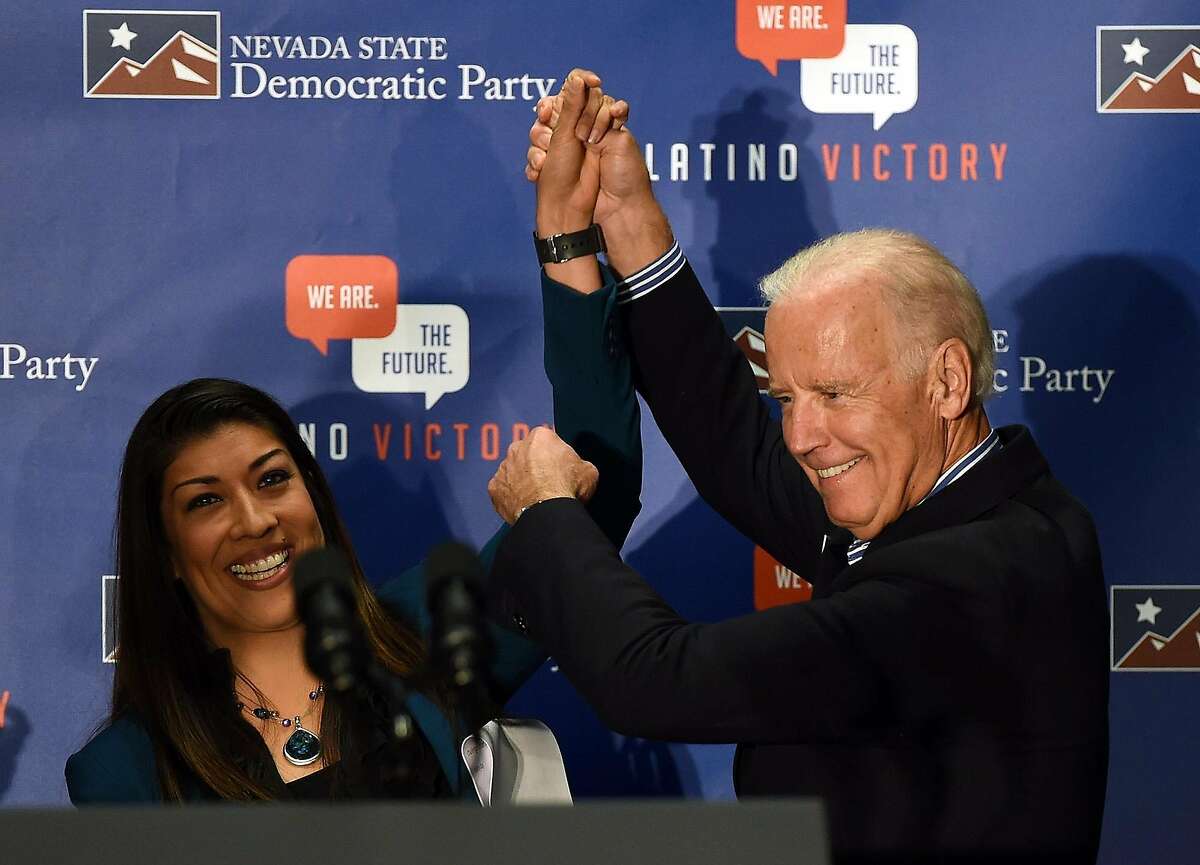 Then-Democratic candidate for lieutenant governor and Nevada Assemblywoman Lucy Flores, left, introduces U.S. Vice President Joe Biden at a get-out-the-vote rally at a union hall on Nov. 1, 2014 in Las Vegas, Nev. Flores wrote that she felt demeaned and disrespected when Biden touched her offstage at a 2014 campaign rally. She said she felt Biden's hands on her shoulders and froze. (Ethan Miller/Getty Images/TNS)