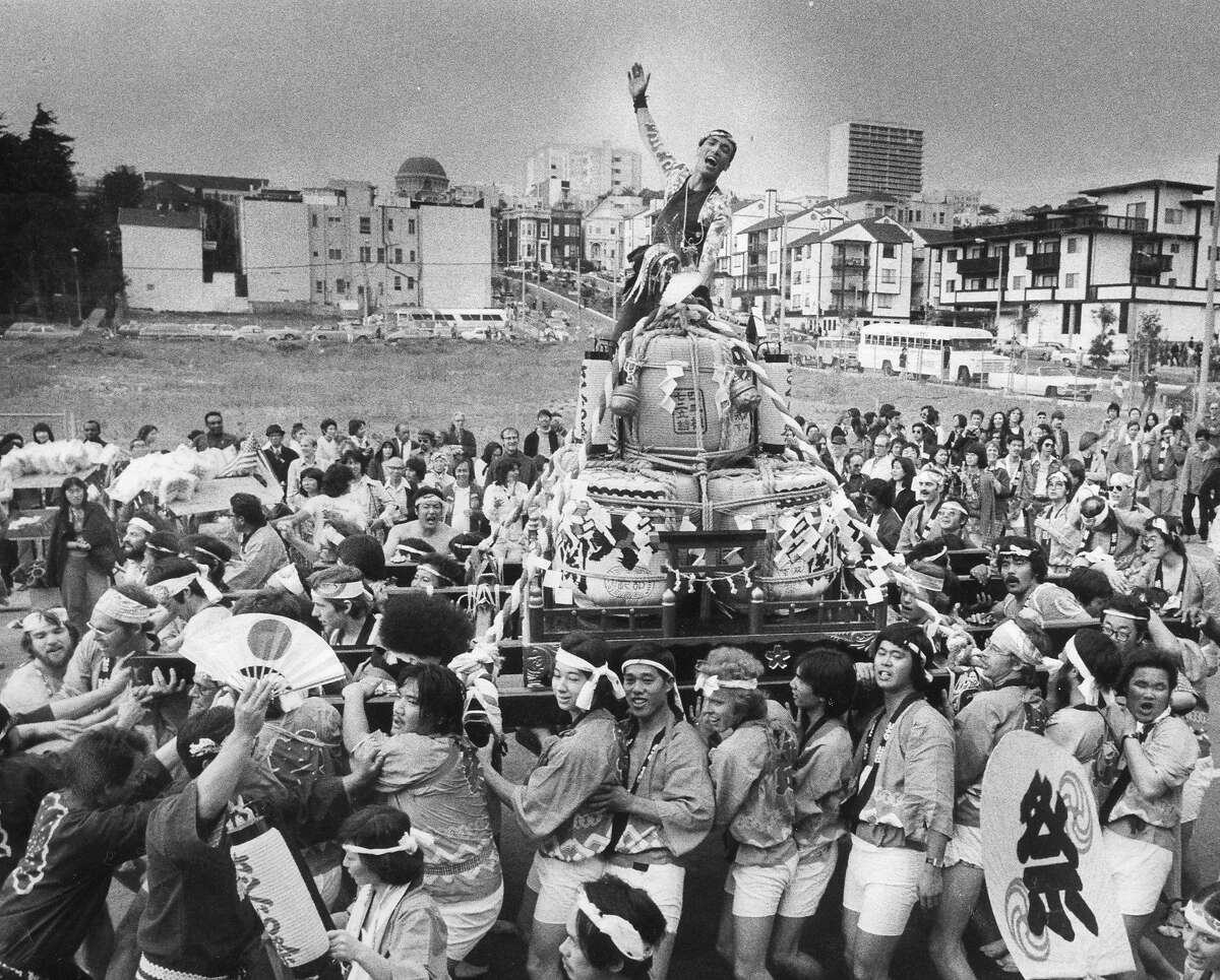 1977年4月24日，在樱花节游行中，游行成员拉着一个清酒桶神社(塔鲁三越)走向日本城
