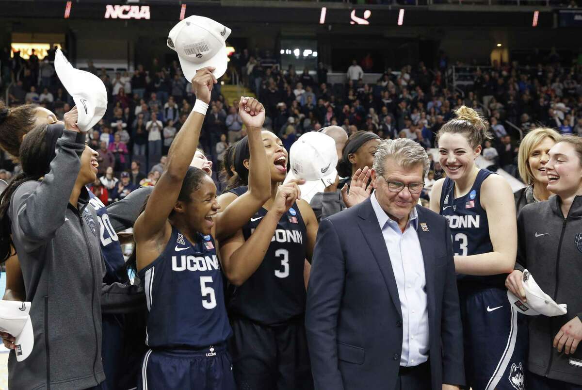 UConn players, including guard Crystal Dangerfield (5), guard Megan Walker (3) and guard Katie Lou Samuelson (33), celebrate with coach Geno Auriemma after defeating Louisville, 80-73, on Sunday.
