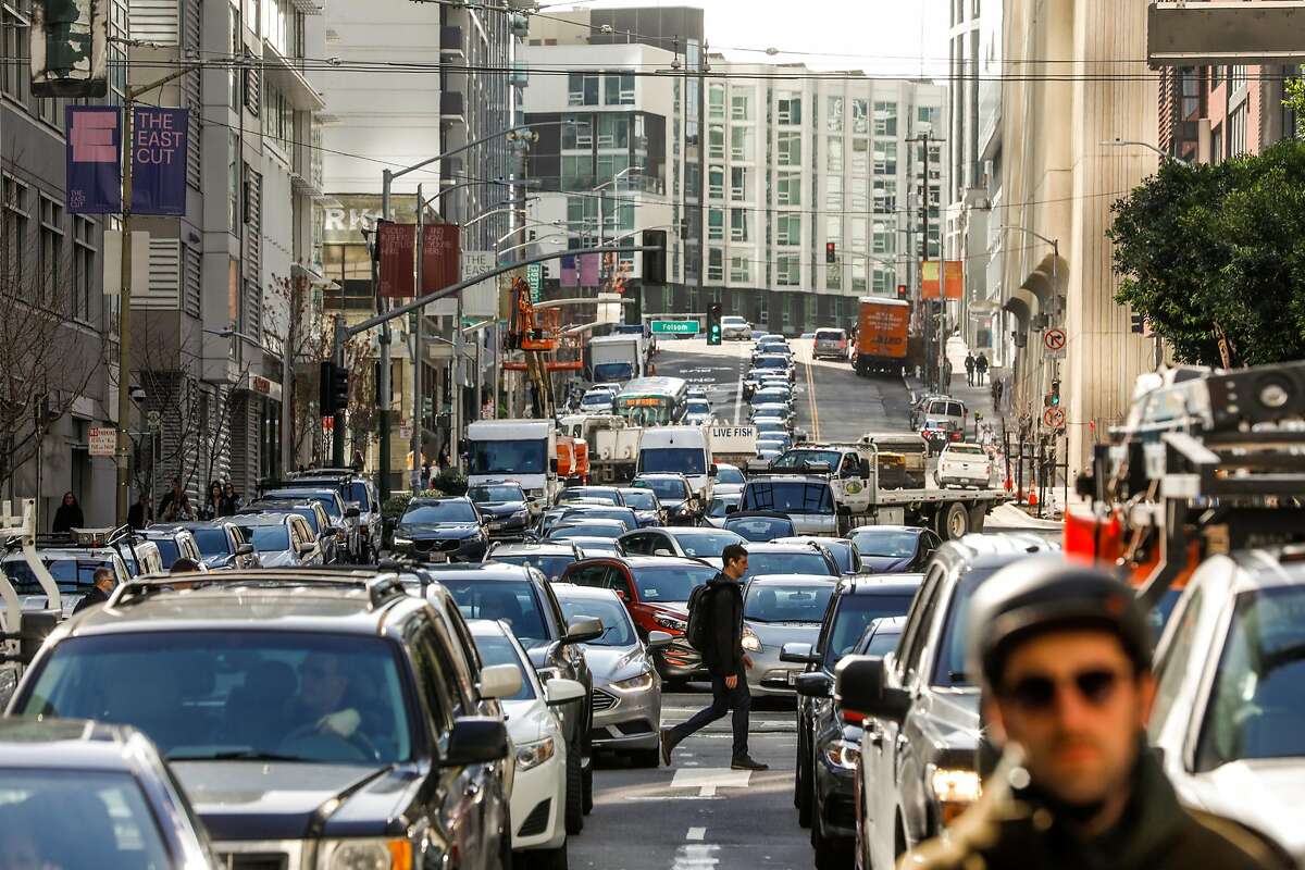 A man crosses Fremont Street passing morning traffic in San Francisco , California, on Tuesday, March 26, 2019.