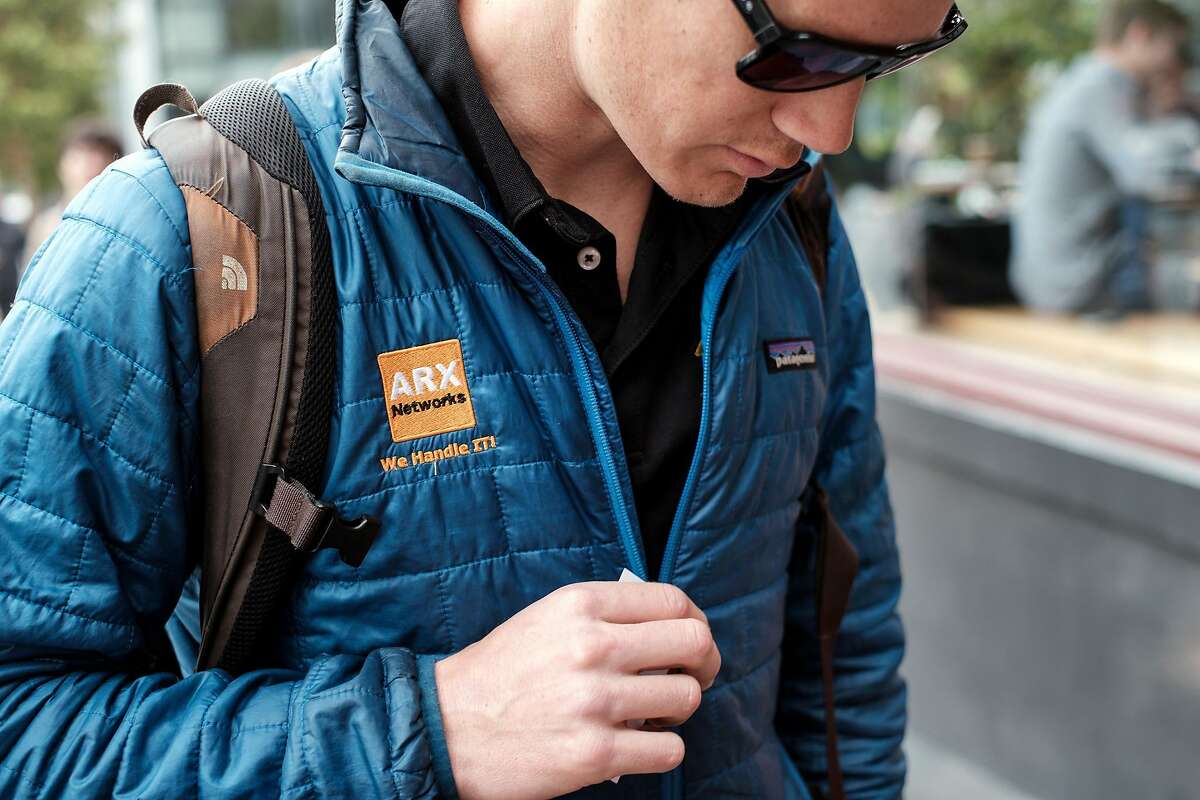 Nick Shmel, an IT worker for ARX Networks, wears a Patagonia jacket that is branded with his company's logo, in San Francisco, Calif., on Tuesday April 2, 2019. In an effort to force a more eco minded approach for tech and finance companies, Patagonia announced that it will stop facilitating corporate branding on it's products for company's that do not reach B corporation status.