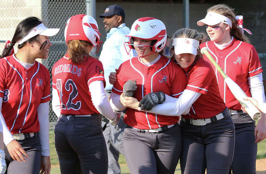 Alton’s Lynna Fischer (middle) gets a hug from Shelby Kulp while heading back to the dugout with Tami Wong (left), Abby Scyoc (12) and Ashlyn Betz (right) after Fischer’s home run in the third inning Tuesday at Alton High. Photo: Greg Shashack | The Telegraph