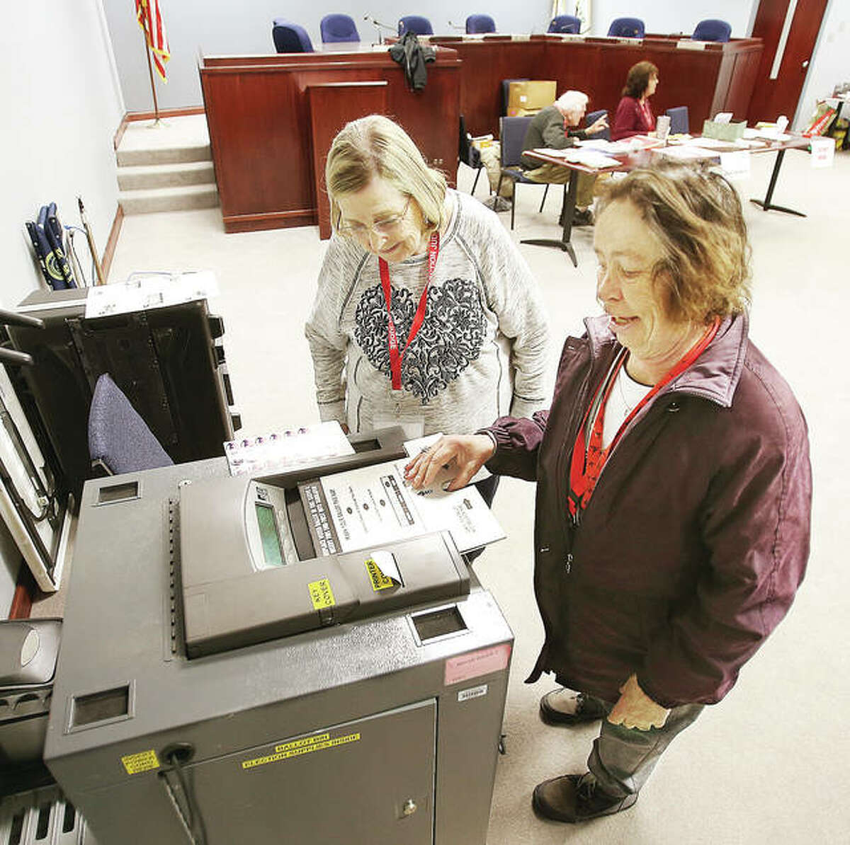 Election judge Lillian Phipps, left, watches as fellow judge Bonnie McClain, of Wood River, feeds her ballot into the tabulation machine Tuesday morning at Wood River Precinct 3, which voted at Wood River City Hall. McClain took advantage of the peace and quiet to cast her vote while waiting. By 9 a.m. only five people had cast ballots in the precinct by that time.