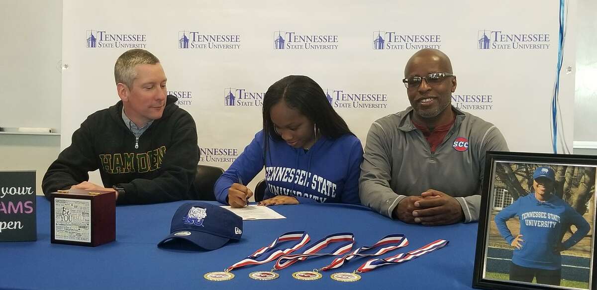 Hamden High senior Tori Roberts, center, signing her national letter of intent to compete in track and field at Tennessee State next season. She is flanked by Hamden outdoor coach Bryce Lindamood, left, and mentor Bob Davis, a longtime track coach in the area.