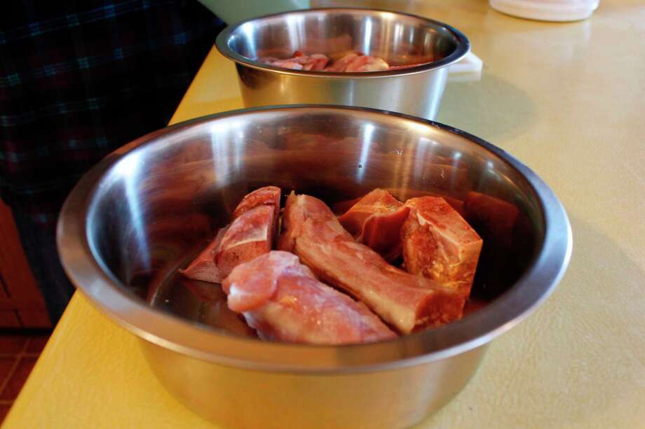 This Feb. 21, 2019, photo shows turkey necks and gizzards that are being served to Gracie and Takaani, two German shepherds who live in Oconomowoc, Wis., with their owners Deb and Joe Colgan. The Colgans started feeding their two previous dogs raw meat seven years ago and continued with Gracie and Takaani because they say they are healthier and have cleaner teeth. U.S. pet owners are increasingly feeding raw, freeze dried or lightly cooked meat and vegetables to their dogs and cats. (AP Photo/Carrie Antlfinger) Photo: Carrie Antlfinger / AP