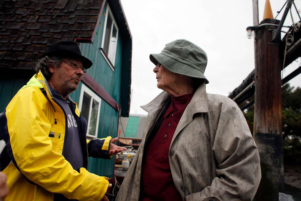 Philip De Andrade, left welcomes neighbor Corinne Woods along the houseboat docks along Mission Creek, Wednesday February 26, 2014, in San Francisco, Calif. Both of them have living among the houseboat community for decades.