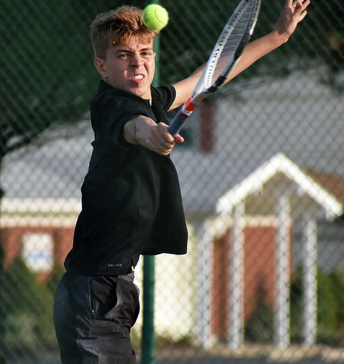 Edwardsville’s Ben Blake hits a backhand shot near the net during doubles action against the O’Fallon Panthers in O’Fallon.