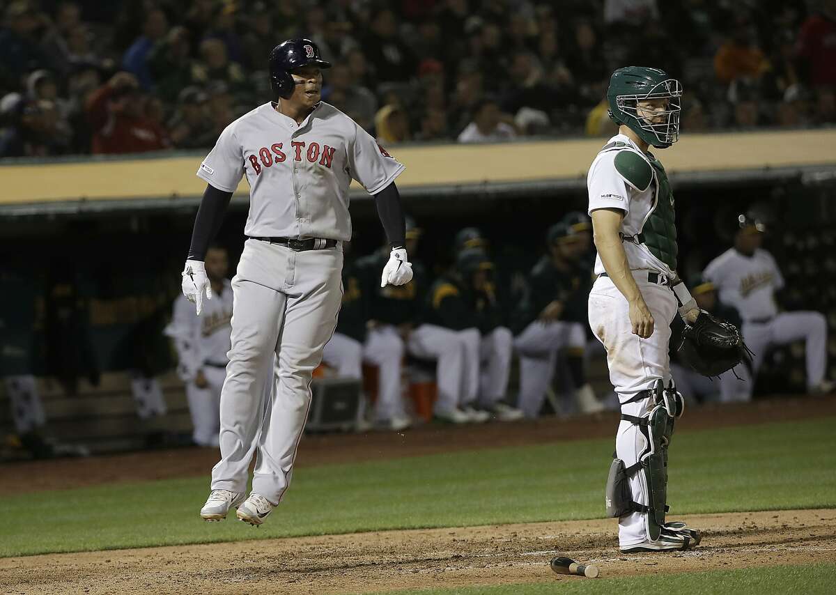 Boston Red Sox's Rafael Devers, left, celebrates after scoring a run, next to Oakland Athletics catcher Nick Hundley during the sixth inning of a baseball game in Oakland, Calif., Wednesday, April 3, 2019. (AP Photo/Jeff Chiu)