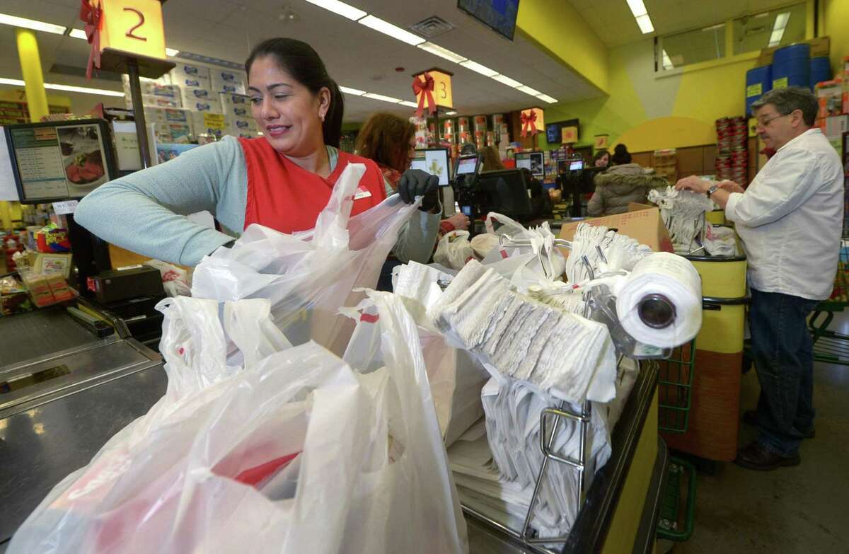 Cashier Beatriz Jimenez bags groceries at CTown in January in Norwalk. Norwalk looks to join surrounding municipalities in enacting a single-use plastic shopping bag ban.