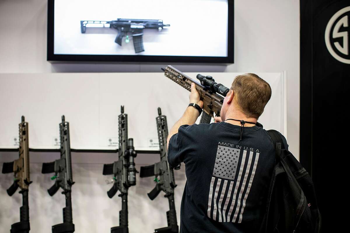 FILE -- A visitor checks out a rifle at a manufacturer's booth at the National Rifle Association's annual meeting in Dallas, May 5, 2018. Guns Down America, a gun control advocacy group, has graded big banks on their policies and practices related to the firearms industry. (Ashley Gilbertson/The New York Times)