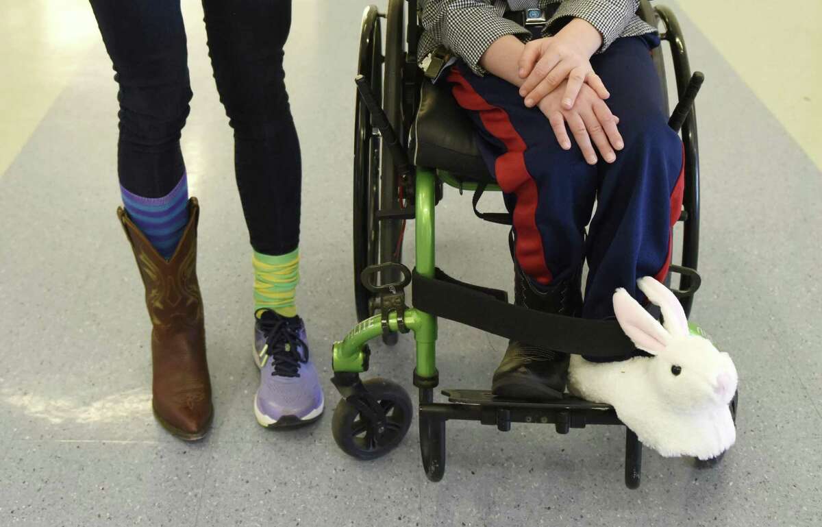 Glenville student Sam Buck, 8, wears mismatched shoes beside para-professional Lisa Gioffre at Glenville School in the Glenville Section of Greenwich, Conn. Thursday, April 4, 2019. Glenville student Sam Buck has Vanishing White Matter disease and many of his classmates and teachers showed support by wearing mismatched shoes and socks, something Buck is known for doing at school. The event raised money for the VWM Families Foundation, which supports families of those suffering from the genetic disorder that affects only about 250 kids in the world.