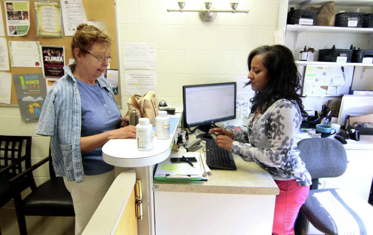 Dispensary Coordinator Sukhdeep Khaira, at right, with the University of Bridgeport's College of Naturopathic Medicine, takes care of a prescription for patient Marlene Bojarski at the college in Bridgeport, Conn., on Wednesday July 13, 2016.