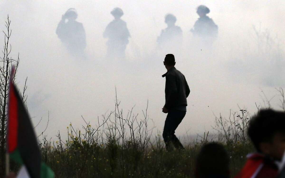 A Palestinian demonstrator is seen with Israeli security forces through the mist in the background, during clashes following a demonstration to plant olive trees in the village of Bizzariya, northwest of Nablus in the occupied West Bank, on March 29, 2019. (Photo by JAAFAR ASHTIYEH / AFP)JAAFAR ASHTIYEH/AFP/Getty Images