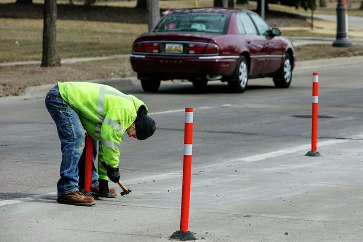 David Lees with the City of Midland Department of Public Works installs a traffic delineator post on Buttles Street Thursday afternoon in Midland. The posts keep drivers from using the far right lane, which has been closed off since March of 2018 during the imposition of a road diet. (Katy Kildee/kkildee@mdn.net)