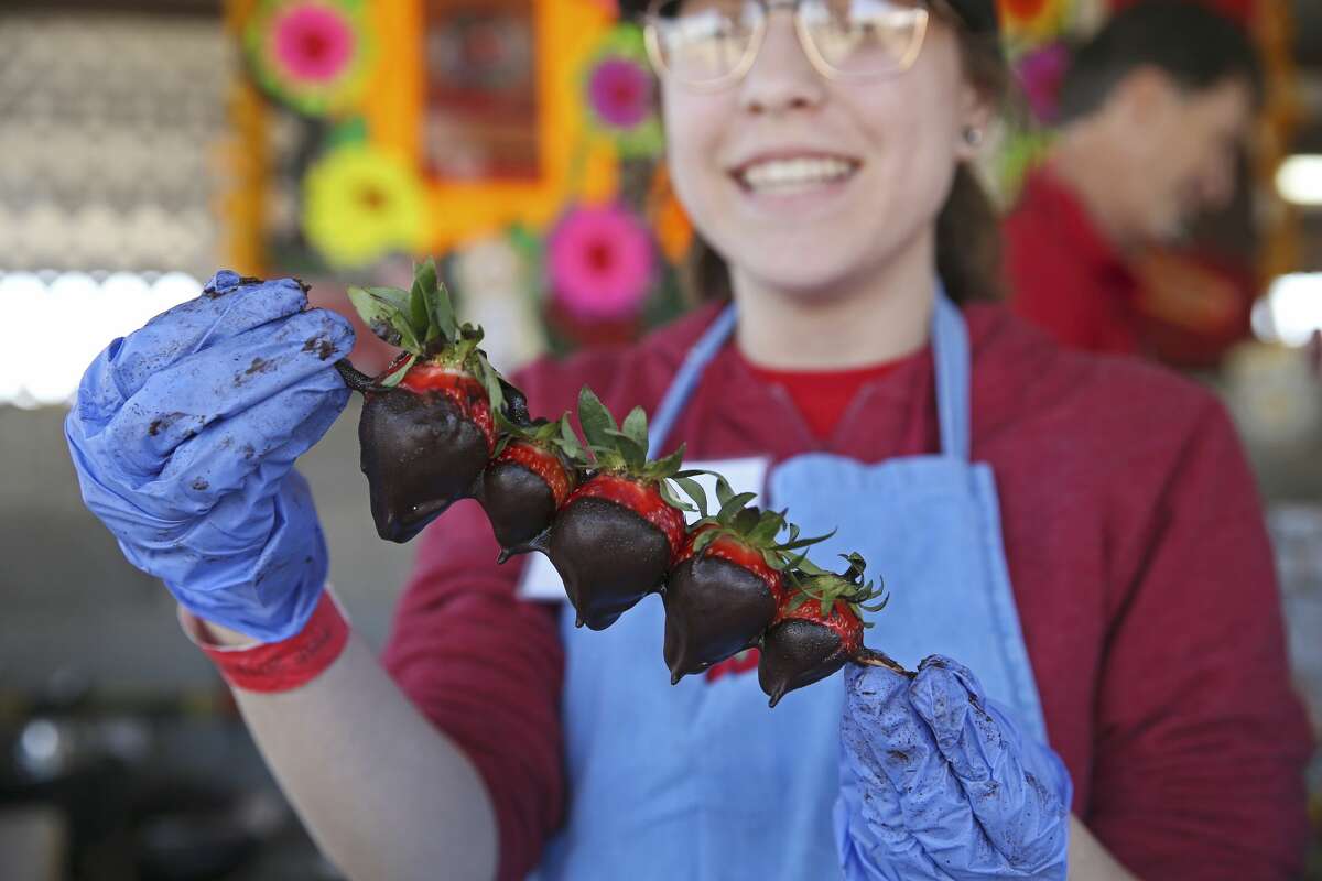 Angelique Rivas shows off chocolate covered strawberries at a booth during the Poteet Strawberry Festival, Sunday, April 7, 2019.