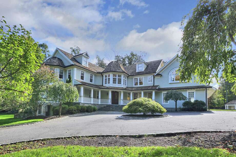 The 13-room sage-colored Nantucket-style colonial house at 10 Hickory Lane sits on a two-acre property close to protected open spaces and the centers of Weston and Westport.