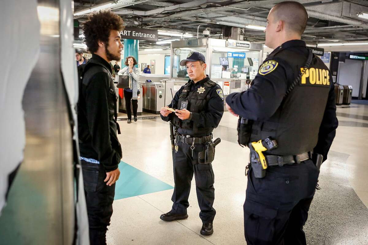 Police officers (L to R) S. Nho and M. Campbell take Jordyn Christo's information and issue him a warning at Powell Station BART entrance after Christo was caught jumping the fare gate on Monday, April 8, 2019 in San Francisco, Calif. Police officers are stationed at downtown stations as BART's large-scale fare evasion enforcement action.