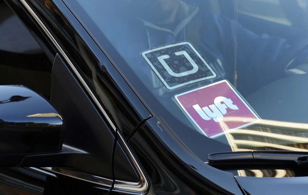 FILE - In this Jan. 12, 2016, file photo, a ride share car displays Lyft and Uber stickers on its front windshield in downtown Los Angeles. Law enforcement agencies and ride-hailing companies are intensifying efforts to warn passengers against getting in without checking to ensure both the vehicle and driver are legitimate. (AP Photo/Richard Vogel, File)