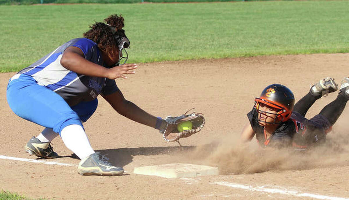 Edwardsville’s Maria Smith (right) avoids the tag from Marquette Catholic third baseman Kyra Green while diving in safely to get first from to third on a sacrifice bunt in the third inning Monday at Edwardsville.
