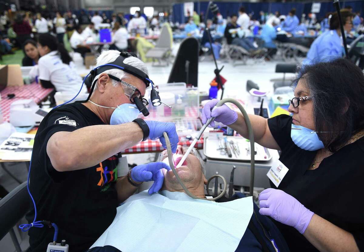 Frank Bensavage, center, of North Branford, gets a filling from dentist Gerald Alexander, left, of New Haven, and dental assistant Cheryl Cappello at the Connecticut Mission of Mercy Free Dental Clinic in New Haven in 2017.