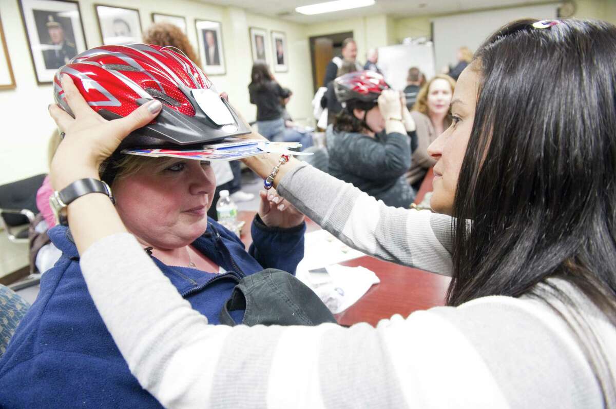 Volunteer Martha Kovacs fits a helmet to Cindi Gioia as the two learn how to fit helmets properly during a training session at the Stamford Police Department, Thursday night in Stamford, Conn., April 26, 2012. Saturday April 28 from 9AM-1PM at the Fairway Market the Stamford Police Association will hold the 18th annual Timothy Coppola Memorial Bike Helmet Giveaway for children ages 4-16. A limited number of toddler size helmets will also be available. This year's helmet giveaway will also include a bike rodeo and K-9 demonstration. Timmy Coppola sustained a traumatic brain injury as a result of a bicycle accident on Aug. 30, 1992, he was not wearing a helmet. Over the years the event has given away 25,000 helmets.