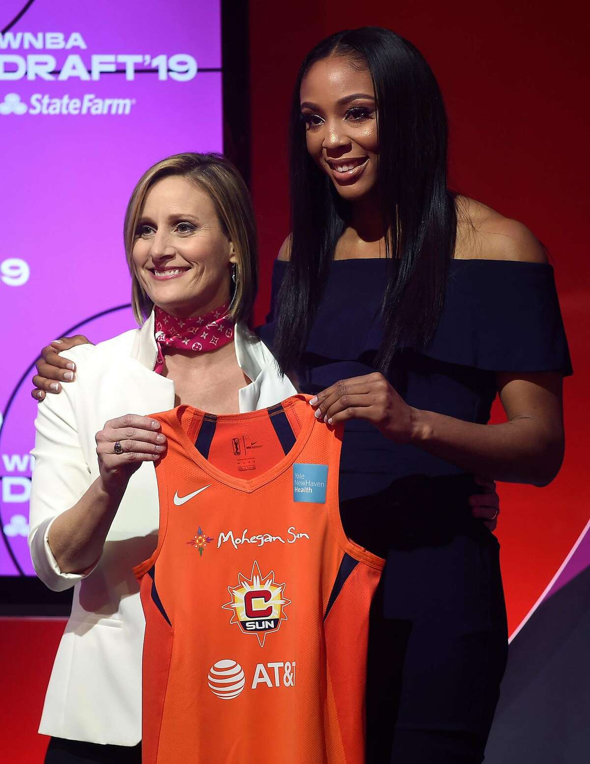 The Connecticut Sun select Kristine Anigwe, right, with the ninth overall pick at the WNBA draft at Nike NY headquarters on Wednesday, April 10, 2019, in New York. Presenting her with her jersey, at left, is WNBA COO Christin Fledgpeth. (Brad Horrigan/Hartford Courant/TNS)