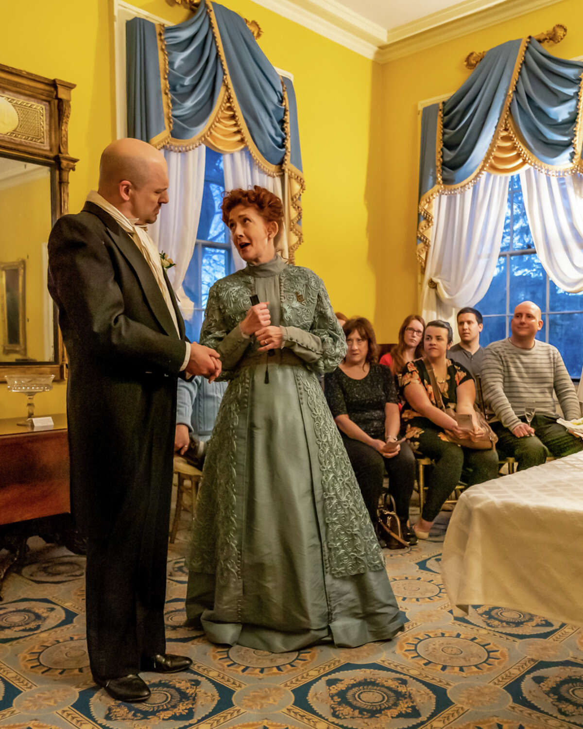 Tony Pallone, left, and Janet Hurley Kimlicko are antagonists in the NorthEast Theatre Ensemble production of Oscar Wilde's "An Ideal Husband," running through April 28, 2019, at Ten Broeck Mansion in Albany. Audience members are in the background.