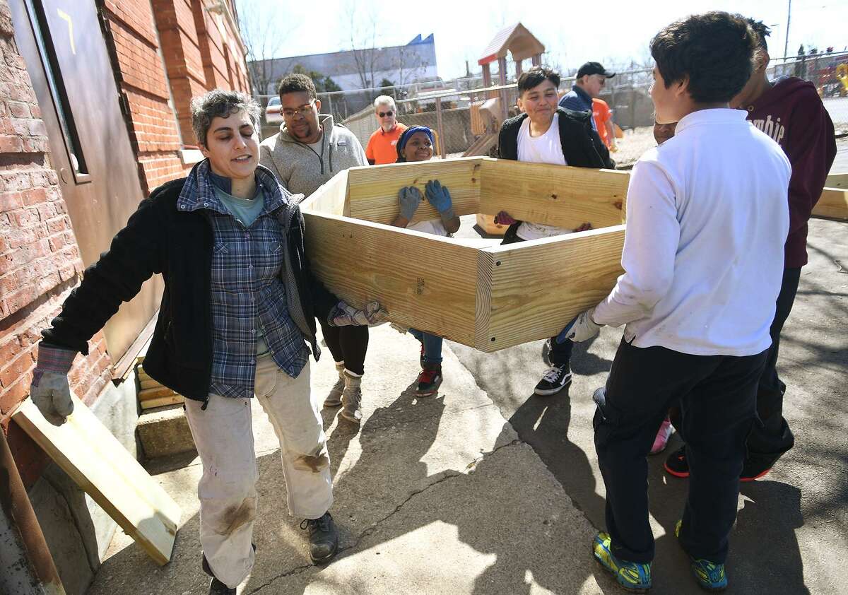 Green Village Initiative Executive Driector Cristina Sandolo, left, and a team of sixth graders carry a hexagonal raised bed to the new school garden at Beardsley School in Bridgeport, Conn. on Wednesday, April 3, 2019.