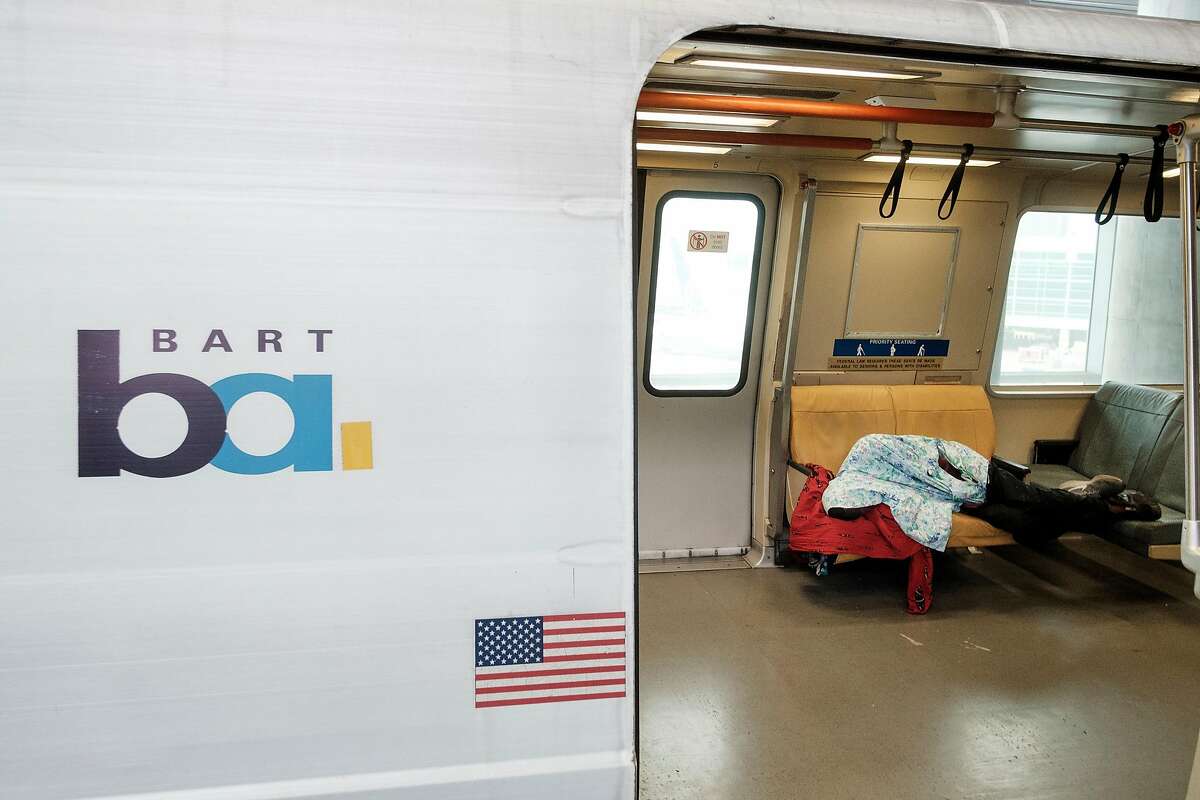 A man sleeps under a blanket on a SFO bound BART train in San Francisco, Calif, on Thursday, April 11, 2019.