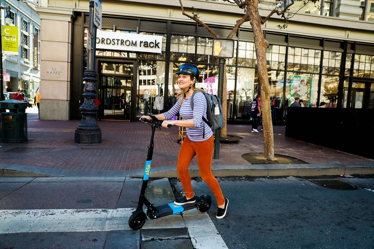 A woman rides a Skip scooter on Market and 5th Streets in San Francisco, California, on Monday, Oct. 15, 2018.