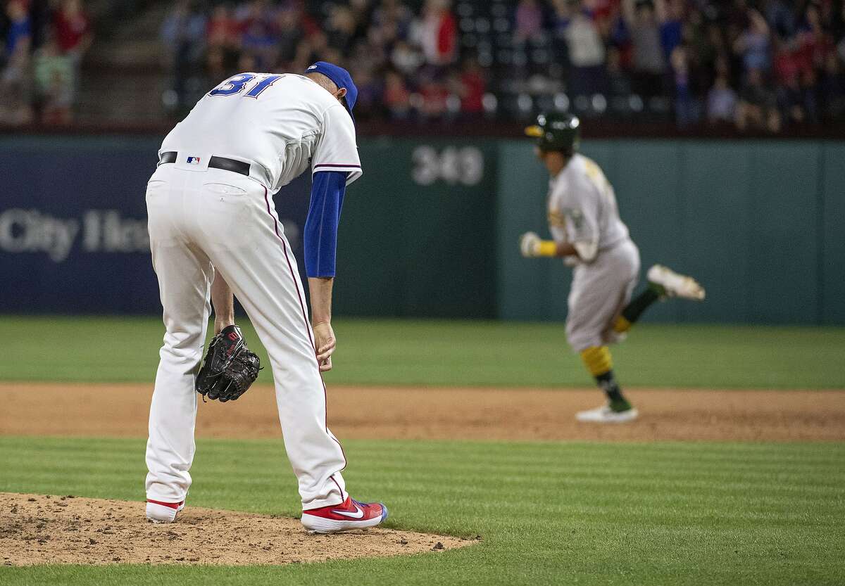 Texas Rangers relief pitcher Chris Martin (31) reacts after giving up a solo home run to Oakland Athletics' Khris Davis, background, during the eighth inning of a baseball game Friday, April 12, 2019, in Arlington, Texas. (AP Photo/Jeffrey McWhorter)