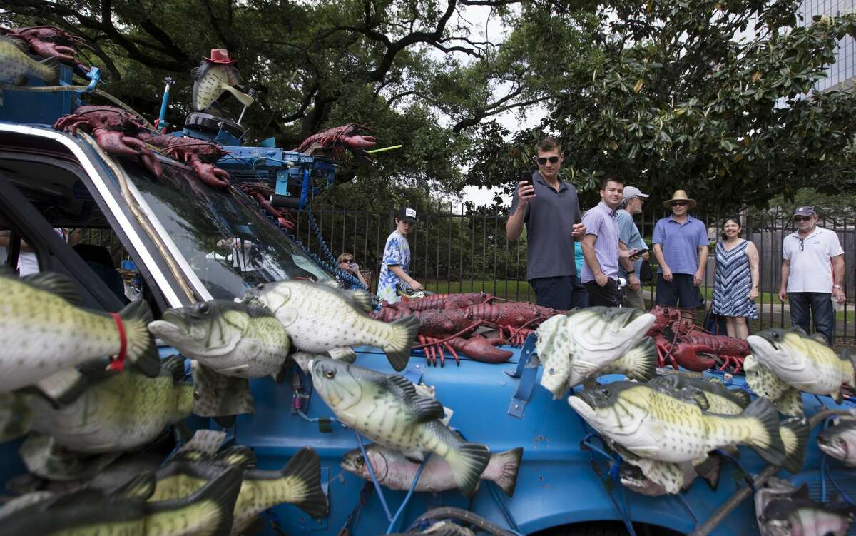 People stop to look and take photographs of the "Billy the Big Mouth Bass" art car at the 32nd Annual Houston Art Car Parade on Saturday, April 13, 2019, in downtown Houston.