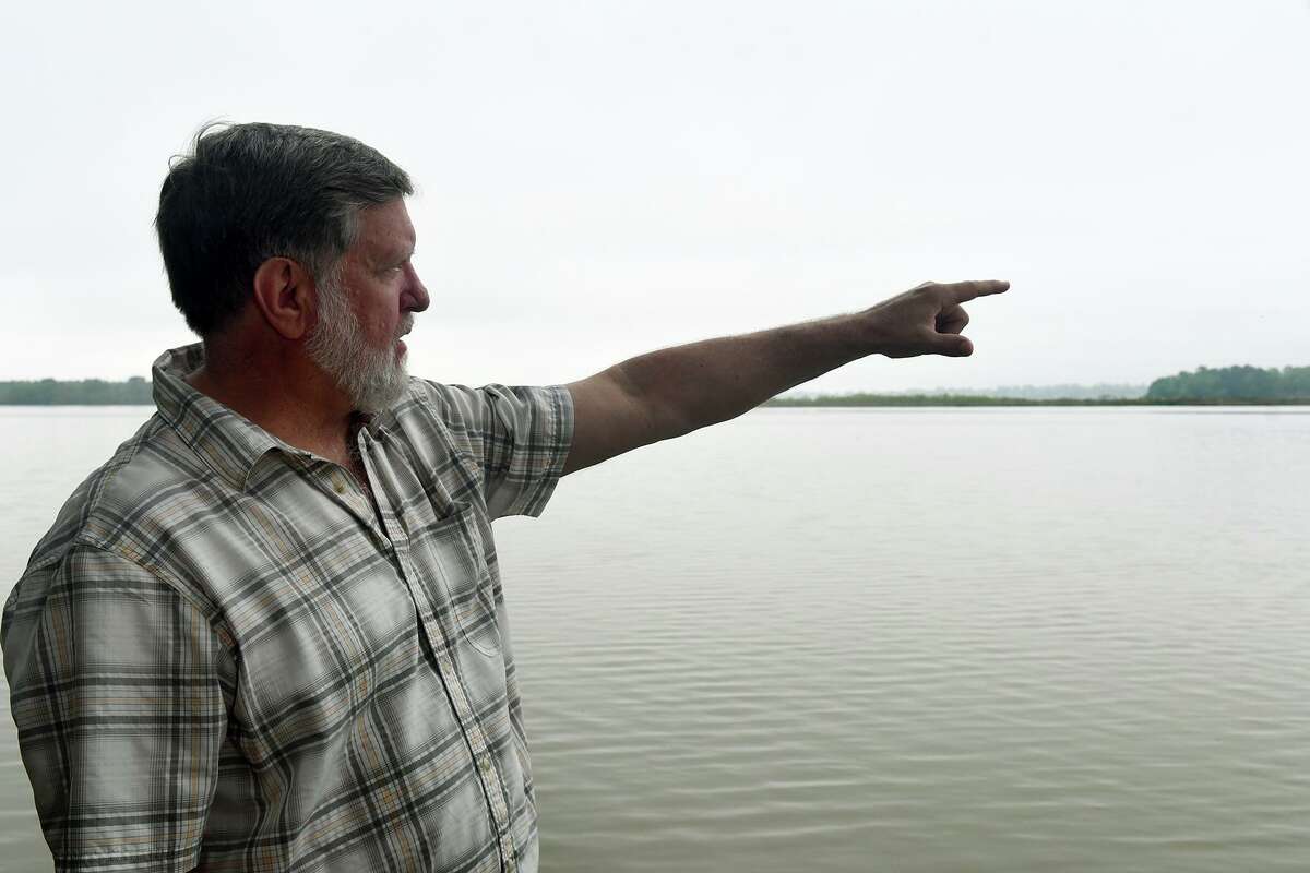 Tim Garfield, a retired Exxon geologist and a resident of Foster Mills Village in Kingwood, points to the island on the lake near Kings Point Trail on April 4, 2019.