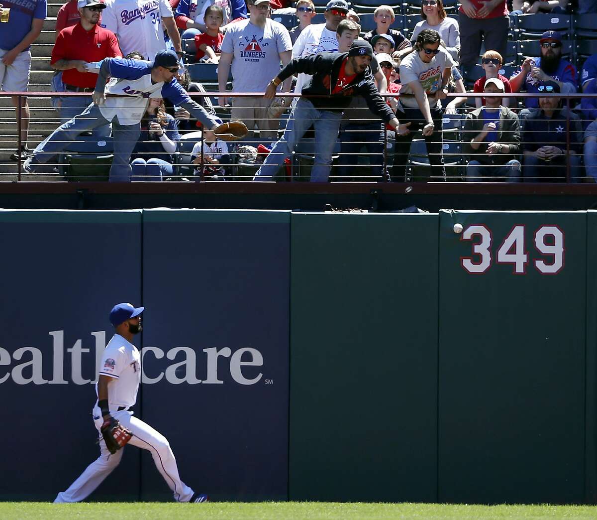 Texas Rangers right fielder Nomar Mazara watches a fans reach out for a Oakland Athletics' Khris Davis double in the first inning of a baseball game in Arlington, Texas, Sunday, April 14, 2019. (AP Photo/Tony Gutierrez)