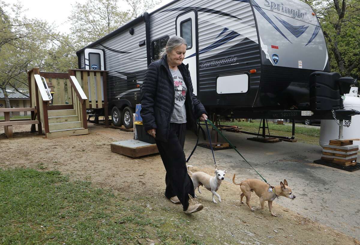 Camp fire survivor, Maureen Curtis, who has stayed at 14 different places since the fire, walks her dogs, Spark and Buddy around the new neighborhood, as she moves into the Bidwell Canyon State Campground on the shore of Lake Oroville, as seen on Mon. April. 15, 2019, in Oroville, Ca. FEMA has installed 69 trailers at the campground for Camp Fire survivors to use.