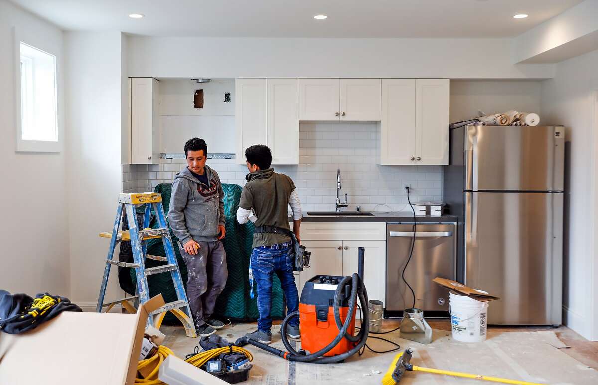 (l-r) Construction workers Robert Sanchez and Felix Guzman chat as they work on an apartment that was converted from a garage into an rental unit on Roanoke Street in San Francisco, California, on Tuesday, March 26, 2019.
